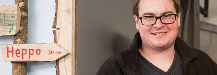 Lächelnde Person vor Holzwand